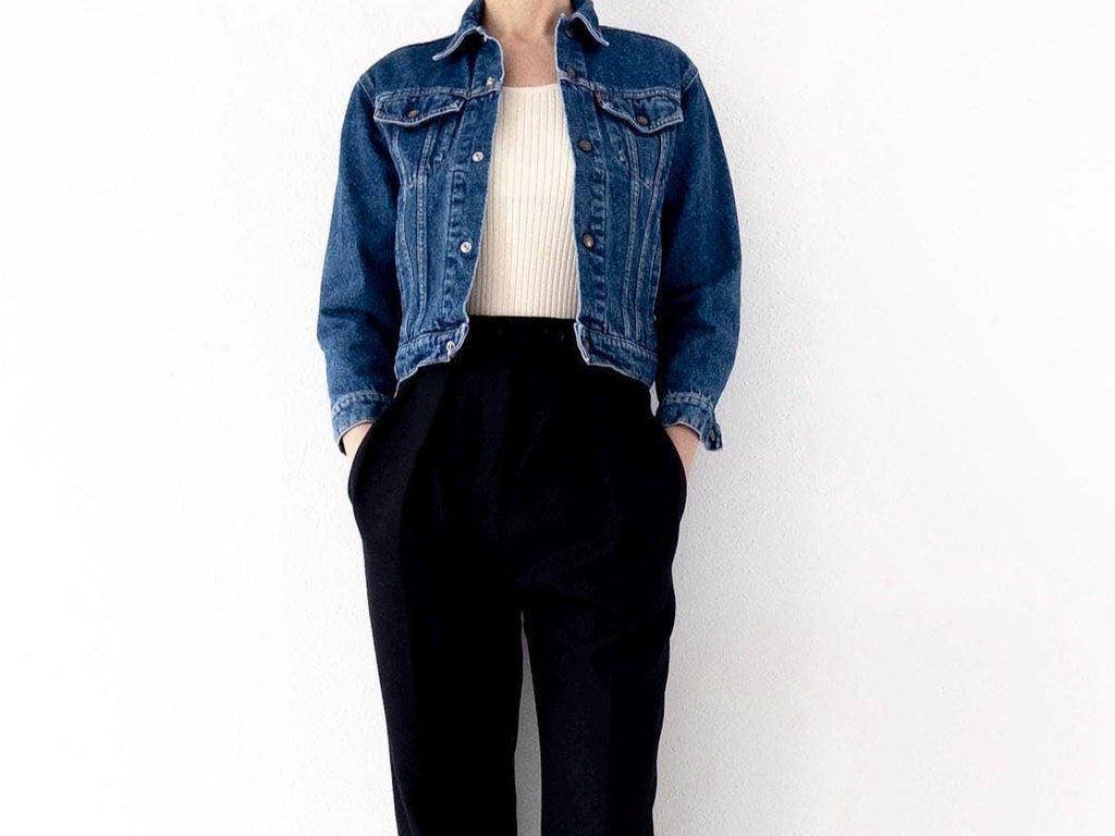 Könnte beinhalten: Eine blaue Jeansjacke mit einem weißen Oberteil und einer schwarzen Hose.