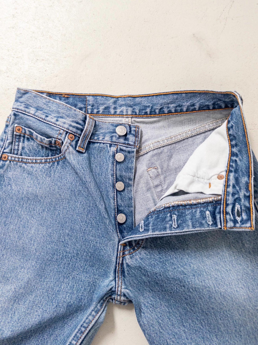 Nahaufnahme des geöffneten Hosenbunds der Levis 501 Vintage Jeans mit Blick auf die authentischen Silberknöpfe der Button-Fly-Knopfleiste