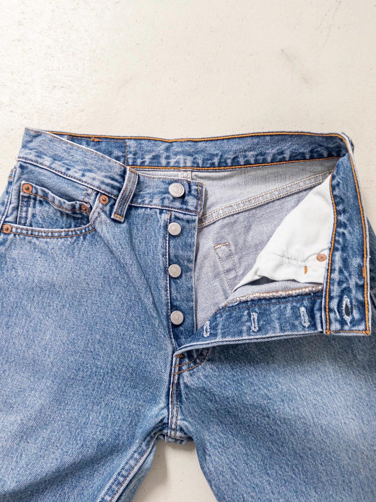 Nahaufnahme des geöffneten Hosenbunds der Levis 501 Vintage Jeans mit Blick auf die authentischen Silberknöpfe der Button-Fly-Knopfleiste