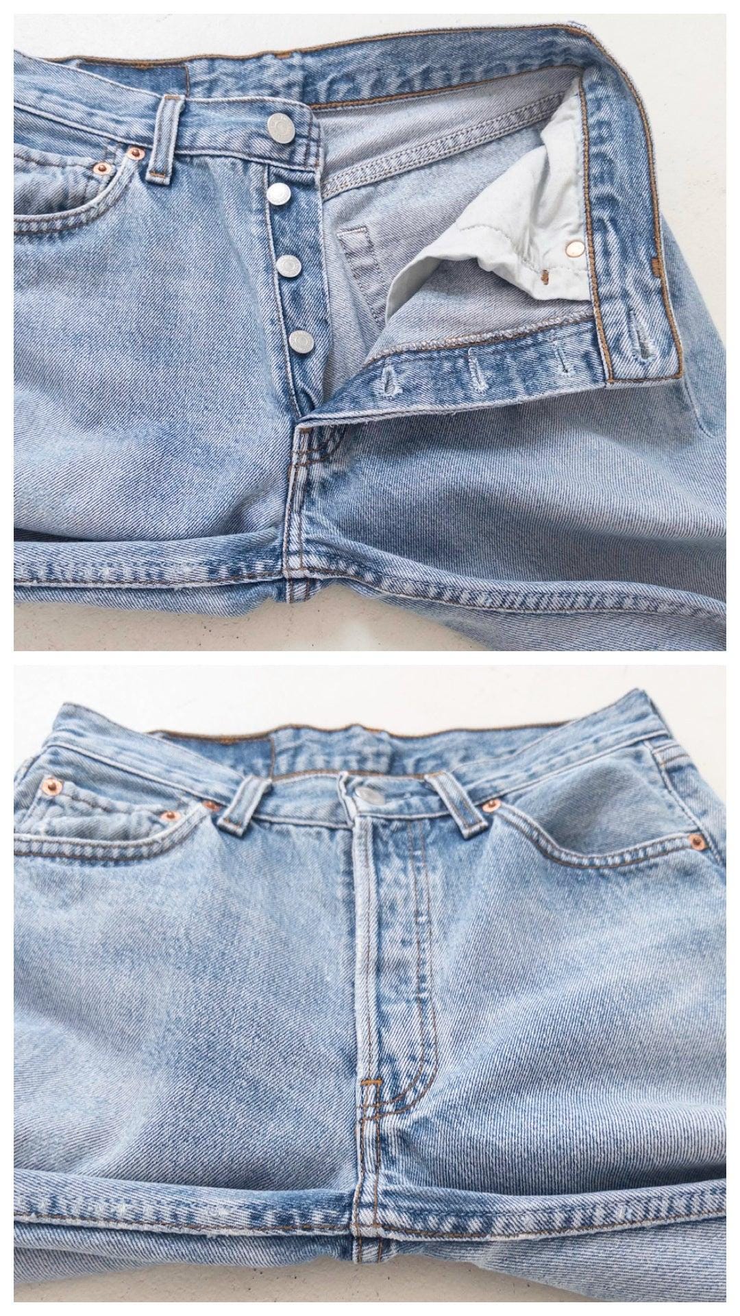 Detailaufnahmen flach liegend: Unten die geschlossene Knopfleiste der Levis 501, oben die geöffnete Button-Fly-Knopfleiste.