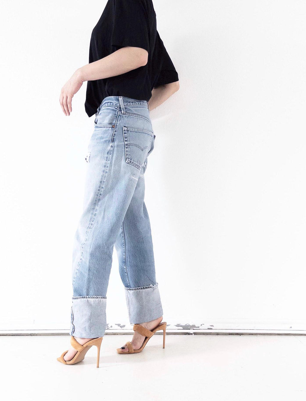 Seitenansicht der hellblauen Vintage Levi’s 501 Selvedge Jeans im soft worn Grunge Distressed-Look mit gekrempeltem Saum. One of a kind Styling mit schwarzem Top und filigranen High Heels. Thrashed Vintage USA Denim von girlstalkvintage.