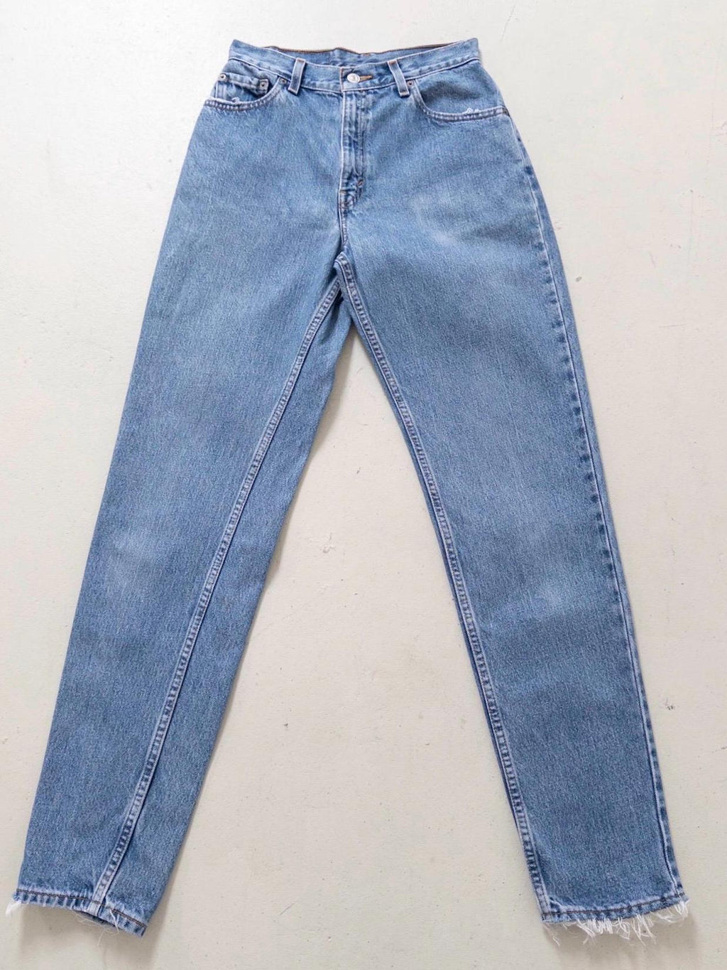 Flatlay Vorderansicht Vintage Levis 550 High Waist Jeans W26 L34 in Hellblau. Liegendes Produktfoto mit Details wie ausgefransten Taschen & Saum