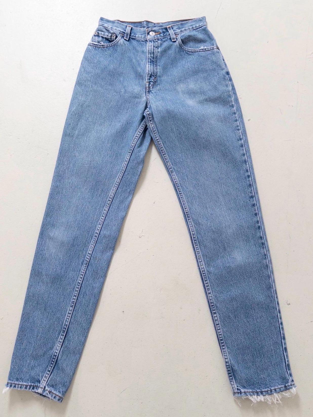 Flatlay Vorderansicht Vintage Levis 550 High Waist Jeans W26 L34 in Hellblau. Liegendes Produktfoto mit Details wie ausgefransten Taschen & Saum
