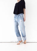 Frontansicht der  Levi’s 501 Selvedge mit authentischer Waschung in Hellblau (Light Wash), leichtem Distressed-Look am Oberschenkel und gekrempeltem Saum.
girlstalkvintage stylt dazu ein locker fallendes schwarzes V-Neck-Top mit halblangen Ärmeln, das  in den Bund gesteckt ist (French Tuck), um eine feminine Silhouette zu betonen.
Dazu elegante, minimalistische Highheels , die dem thrashed Denim-Look eine feminine Note verleihen und die Beine optisch verlängern.