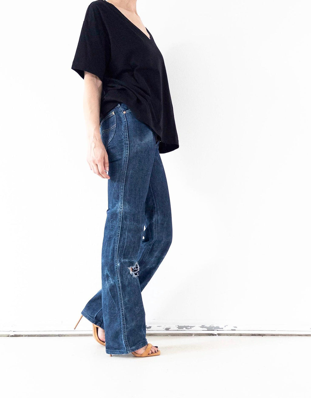Model trägt seltene 70s Lee Flared Jeans Schlaghose mit ausgebleichten Sun-Faded Details und distressed Details am Knie, zu sehen von der Seite