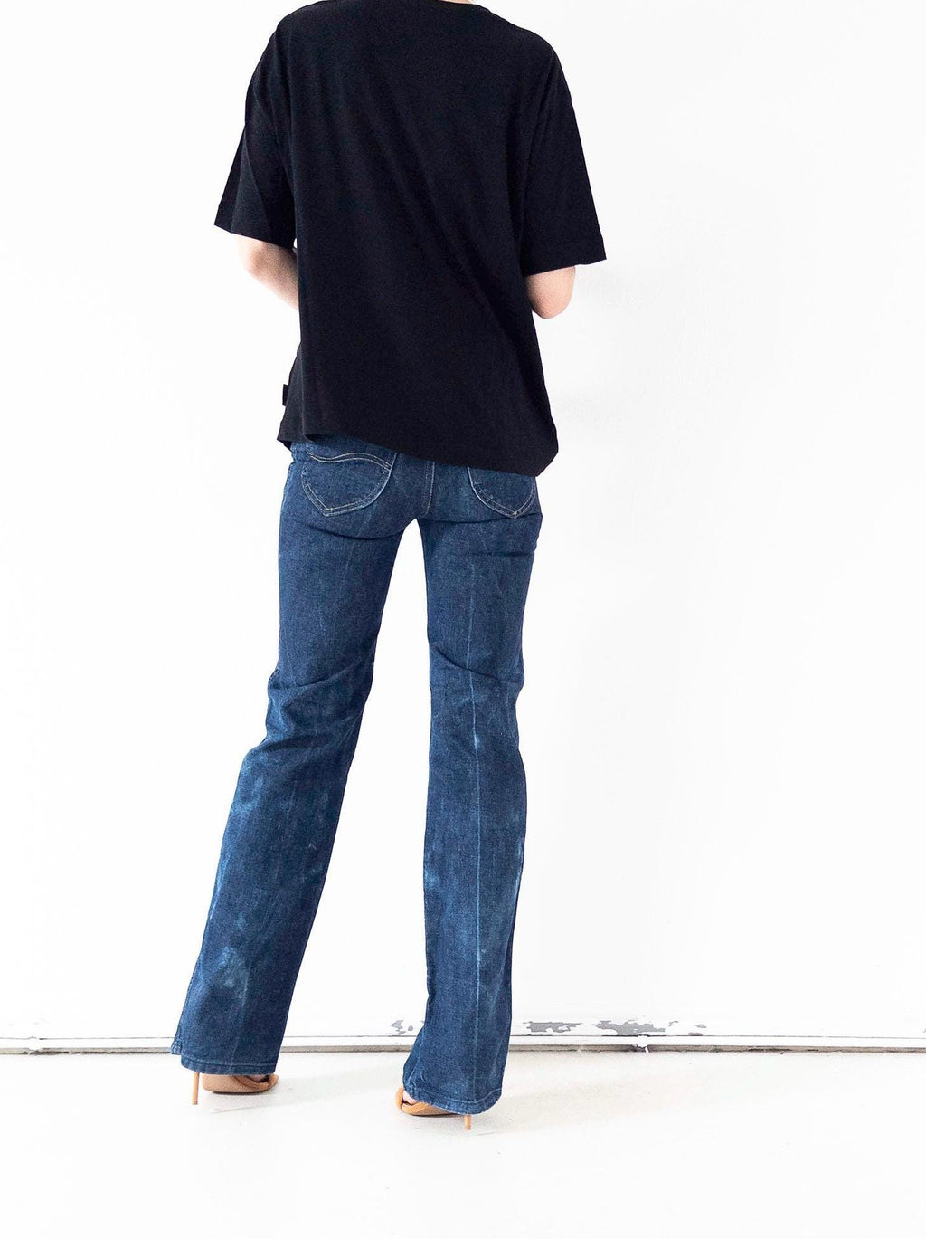 Rückansicht der one of a kind super soft worn in Vintage 70er Lee Bellbottoms Jeans mit Schlag & Passform am Po, schwarzes Top und High Heel Mules in Nude für den perfekten Style für Tag und Nacht.