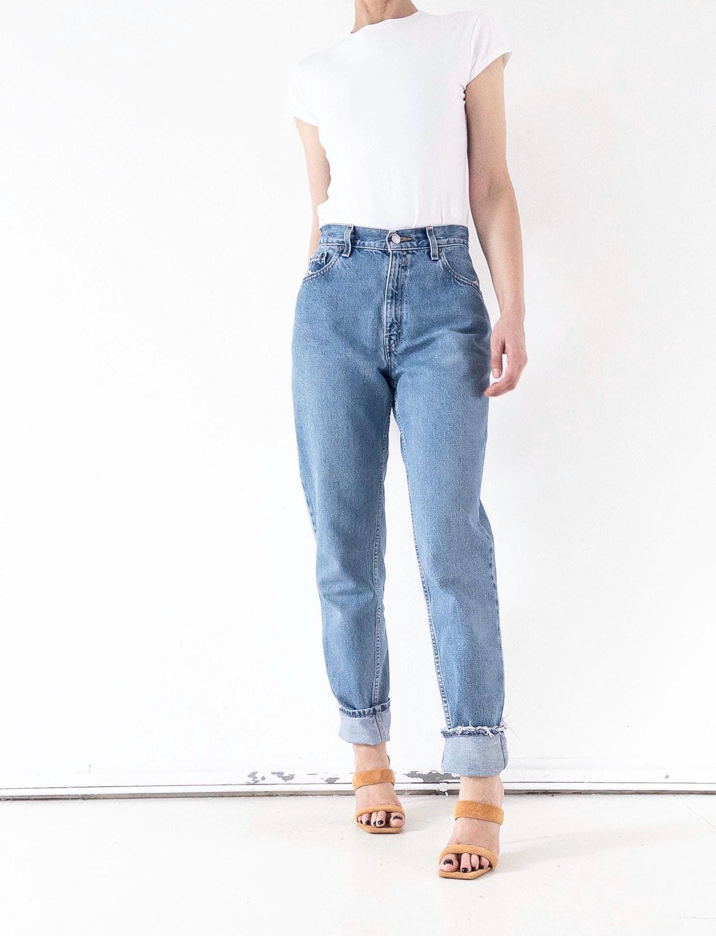 Klassisches 90er Outfit: Blaue Levi's 550 Relaxed Fit Mom Jeans getragen mit weißem T-Shirt & Absatzsandalen – girlstalkvintage stylt die stonewashed Jeans lässig und cool für den Alltag.